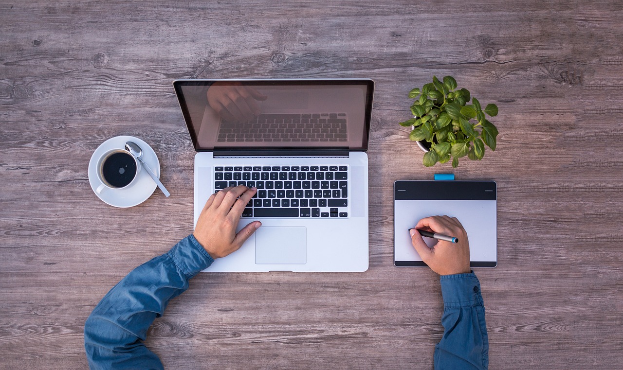 An organised workspace with a laptop, notebook and coffee